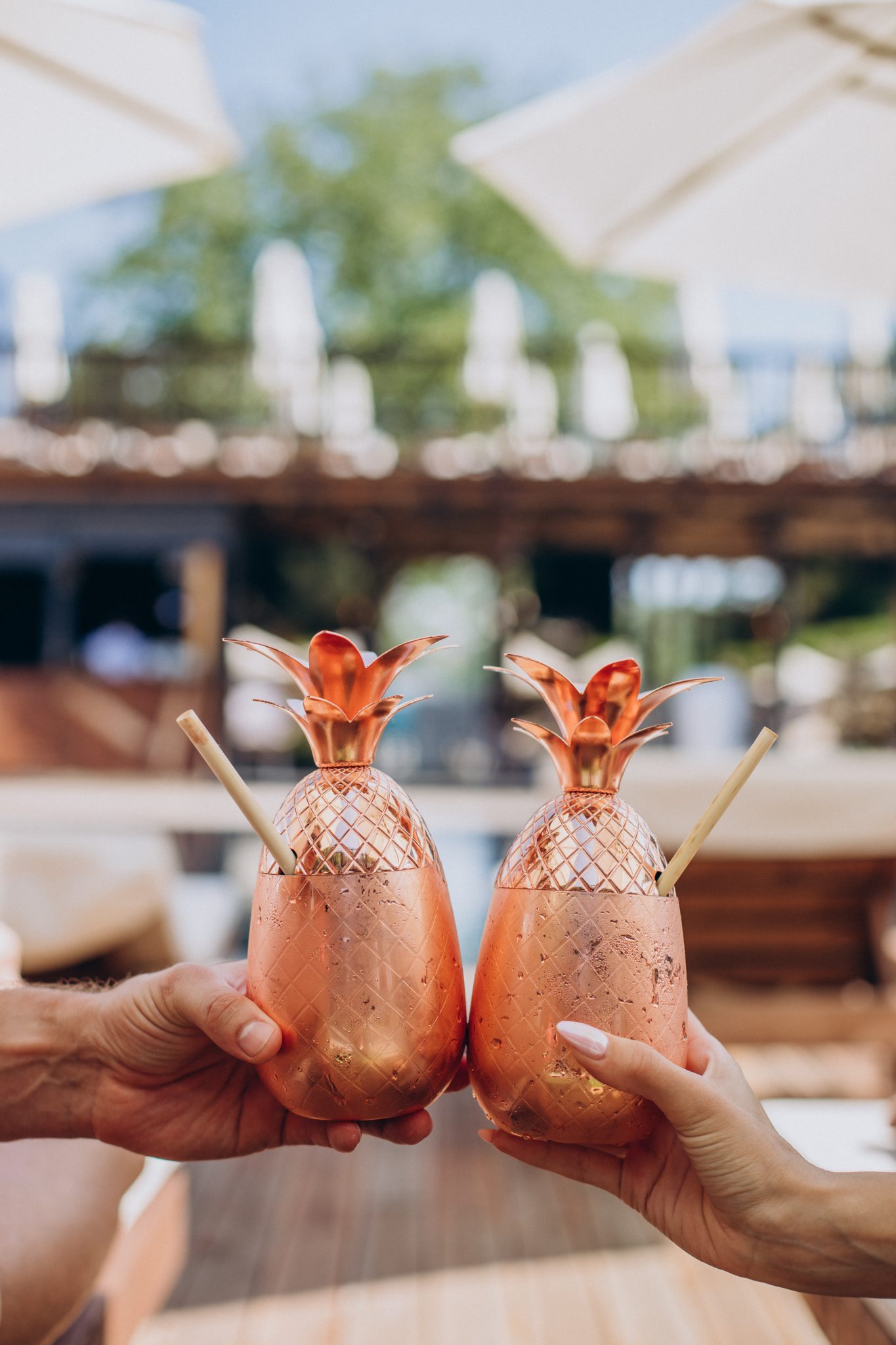 Male and female hands holding cocktails by the pool